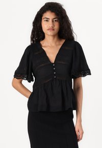 Black blouse made of light fabric with a V-neck, short ruffled sleeves, and decorative eyelet trim. Features buttons along the front.