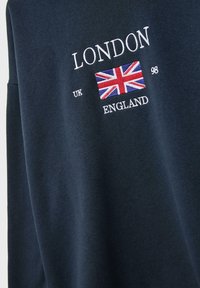 Námornícky modrý sveter s bielou vyšívanou potlačou "LONDON", dizajnom vlajky a "UK 98 ENGLAND", s hladkou textúrou a uvoľneným strihom.