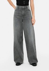 Grijze denimbroek met wijde pijpen en studs als versiering. Voorzien van vijf zakken, een hoge taille en een gestructureerde afwerking.