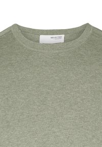Green knit crew neck sweater made from soft fabric with a textured finish. Label reads "SELECTED / HOMME." Simple, casual design.