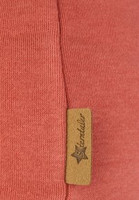 Coral cotton fabric with a ribbed texture; features a stitched tan leather label with "Sterntaler" and a star accent.