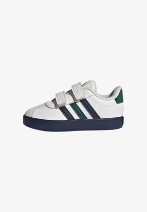 Scarpa da ginnastica bianca con suola blu scuro, due strisce in velcro e righe verdi e blu scuro sul lato, vista dal lato esterno.
