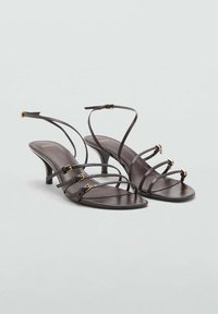 Bruna läderklackade sandals med flera tunna remmar och spännen i guldton. Klackarna är smala och i stilettmodell. Slät yta.