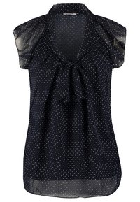 Blouse sans manches bleu marine à petits pois blancs, avec un nœud au niveau de l'encolure et un tissu léger et transparent aux épaules et à l'ourlet.