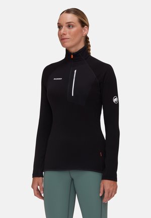 Black long-sleeve top with a high collar, half zip, chest pocket, and logo. Features textured fabric and contrast stitching details.