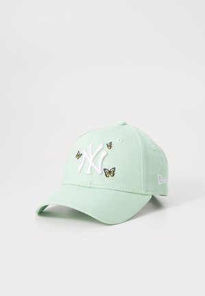 Gorra verde menta de algodón con visera curva. Presenta un logo bordado en blanco y pequeños apliques de mariposa en negro y amarillo.
