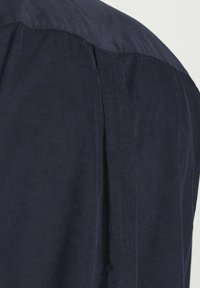 Camicia in corduroy blu navy con texture a coste, pieghe sottili sulle spalle e un design morbido del yoke nella parte alta della schiena.