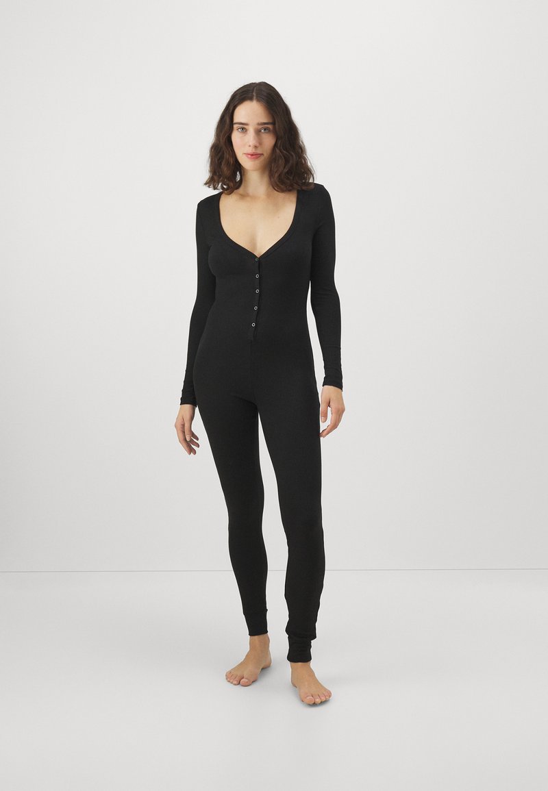 Bodysuit noir à manches longues avec un décolleté en V profond, fermeture par boutons à l'avant, silhouette ajustée et texture côtelée. Sans motifs ni accents.
