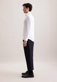Witte lange mouwen shirt gecombineerd met een donkere broek en zwarte leren schoenen. Het shirt heeft een klassieke kraag en een slim fit ontwerp.