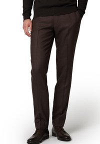 Ciemnobrązowe, dopasowane spodnie wykonane z gładkiego materiału o prostym kroju. Posiadają przednie zakładki i są noszone z brązowymi eleganckimi butami.