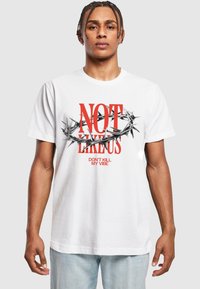 Hvid bomulds T-shirt med rød tekst "IKKE SOM OS" og "DREJ IKKE MIN STEMNING," samt et grafisk sort, spidst krone motiv. Casual pasform, korte ærmer.