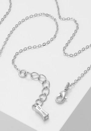 Silver chain necklace with lobster clasp and rectangular charm engraved with "TED BAKER" on white surface.