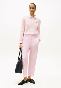 Roze gestructureerde trui met witte kraag, lichtroze op maat gemaakte broek, zwarte loafers en een zwarte tote bag. Eenvoudige, geometrische ontwerpelementen.