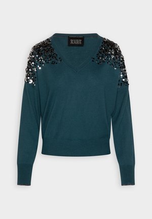 Pull en teal avec un col en V, des manches longues et des détails en sequins sur les épaules. Texture douce et ourlet ajusté. Étiquette de la marque visible.