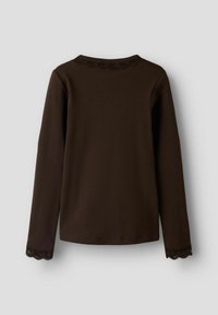 Mørkebrun ribbestrikket genser med lange ermer og blonderkant på halsen og ermene, lagt flatt på en lys bakgrunn.