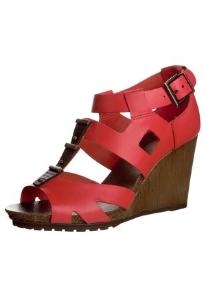 Rode sleehak sandaal met uitgesneden ontwerp, verstelbare enkelband en gespdetail. Houten sleehak voegt textuur en contrast toe.
