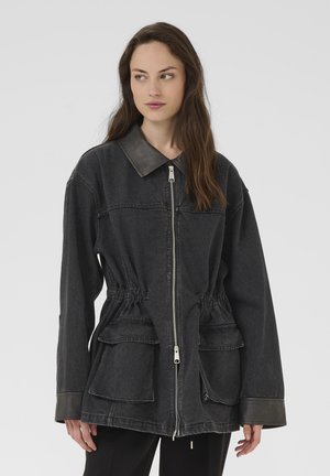 Jachetă din denim negru cu guler din piele gri, închidere frontală cu fermoar, talie ajustabilă și două buzunare mari în față. Mâneci lungi cu manșete tonale.