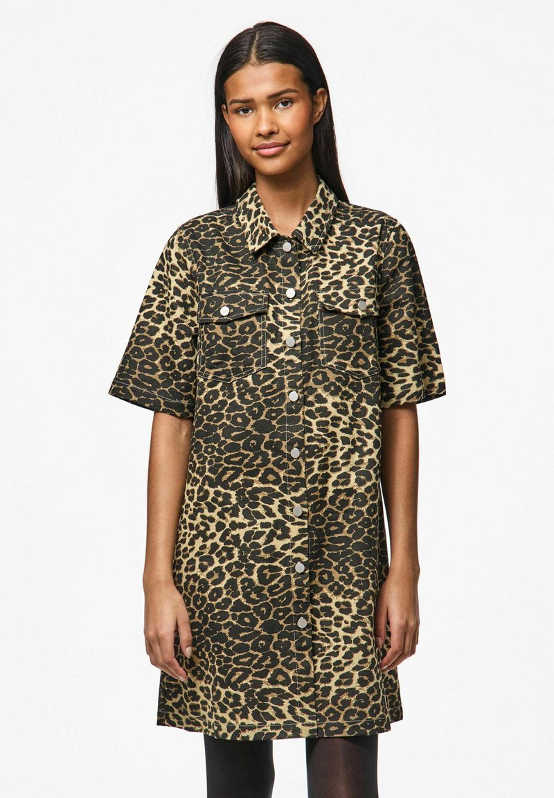 Abito camicia a maniche corte in stampa leopardata, con chiusura a bottoni, due taschini sul petto, colori nero e beige, e una vestibilità comoda.