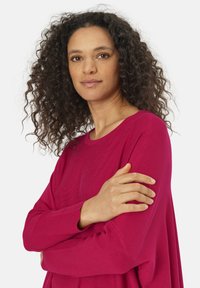 Pull à manches longues magenta avec une coupe d�écontractée et une texture côtelée. Dispose d'un col rond et de manches amples.