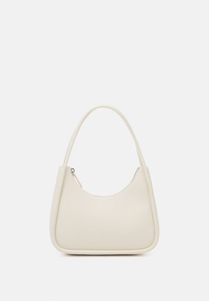 Mała torebka w kolorze ecru z zaokrągloną górą, pojedynczą rączką i zamkiem błyskawicznym na jednolitym jasnym tle.