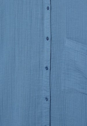 Lyseblåt tekstureret stof med lodret knaplukning og en firkantet brystlomme på højre side.