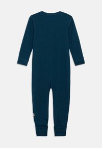 Tmavomodrozelené nažehlené detské tričko s dlhým rukávom s manžetami na nohách a malou viacfarebnou pruhovanou značkou na nohe.