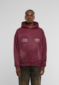 Felpa in cotone borgogna con tasca frontale, cappuccio con cordino e testo stampato bianco sul lato sinistro del petto e sulla manica.