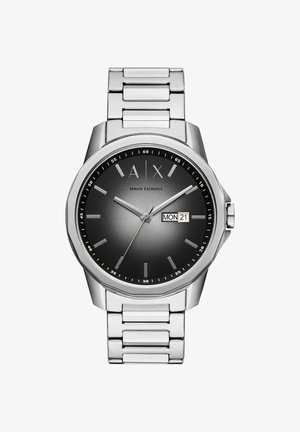 Sidabrinis nerūdijančio plieno laikrodis su apvaliu pilku ciferblatu, sidabriniais valandų žymekliais ir datos rodymu, nurodančiu "21". Yra sujungtas apyrankės dizainas.