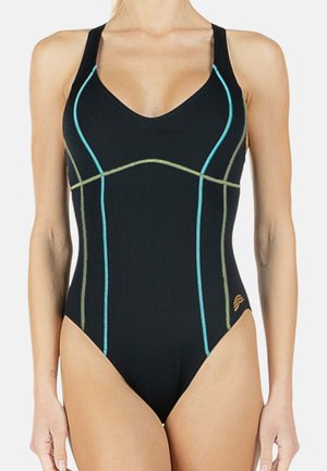 Donna che indossa un costume intero nero con cuciture verticali e curve blu e verdi e un piccolo logo sull'anca sinistra.