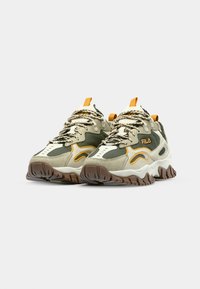 Zapatillas verdes y beige con parte superior texturizada, acentos naranjas y suelas gruesas con relieve. Presentan cordones multicolores y un cuello acolchado.