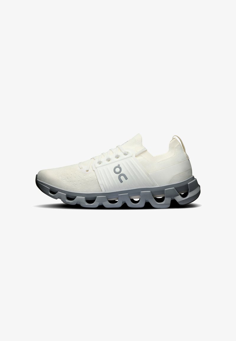 Lace-up running shoes with a white fabric upper, textured detailing, light gray rubber sole featuring distinctive cutouts, and logo accent.