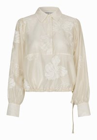 Blouse crème à manches longues avec une broderie florale subtile, un col, des poignets boutonnés et un ourlet élastique avec des liens réglables sur le côté.
