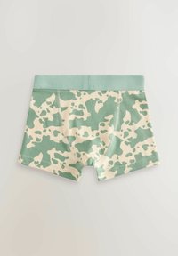 Boxers pour garçons à motif camouflage vert et beige avec une ceinture verte unie, posés à plat sur une surface claire.