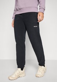 Black tapered jogger pants made of fleece, featuring two side pockets, elastic cuffs, and a Columbia logo on the front.
