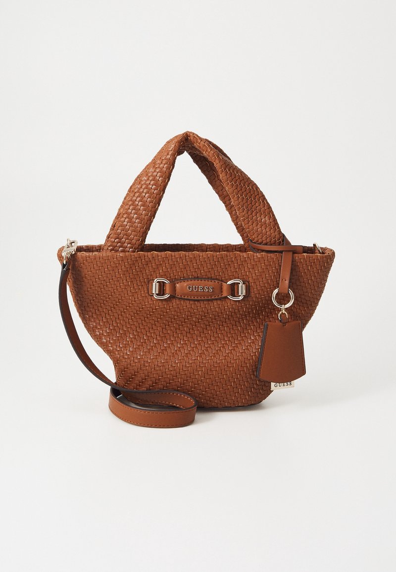 Sac à main en cuir tissé marron avec des poignées courtes, une bandoulière amovible et une étiquette avec le logo Guess à l'avant et sur le côté.