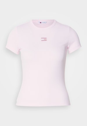 Svijetlo ružičasta majica kratkih rukava izrađena od rebrastog materijala, s malim pravokutnim logotipom u sredini. Prilagođeni kroj s okruglim izrezom.