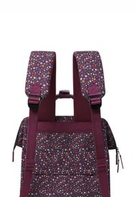 Rucksack mit floralem Muster in Lila-Tönen, ausgestattet mit gepolsterten Trägern, verstellbaren Schnallen und einer seitlichen Tasche mit Reißverschluss.