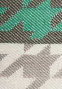 Textil mit einem Hahnentrittmuster in türkis und grauen Abschnitten, mit einer strukturierten Stoffoberfläche und abwechselnden Farbbalken.
