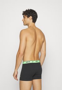 Schwarze Boxershorts mit einem grünen Nike-Logo am Bund. Ausgestattet mit einem enganliegenden Design und weichem Stoff. Schlichter und minimalistischer Stil.