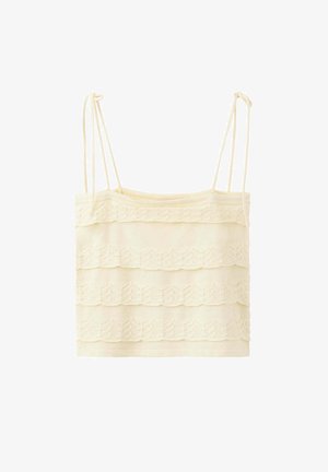 Top court sans manches couleur crème avec détails en dentelle superposée et fines bretelles réglables sur fond blanc.