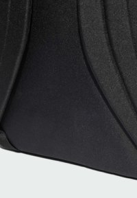 Sac noir en tissu texturé, présentant des accents courbés et un design épuré. La surface a un aspect mat avec un léger brillant.