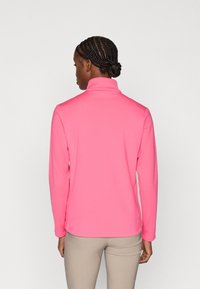 Pink long-sleeve pullover with a high collar, made of smooth fabric. Features fitted sleeves and a seamless back design.