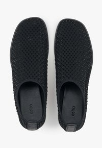 Czarne buty wsuwane z teksturowaną plecionką, zaokrąglonym noskiem i gładkimi czarnymi podeszwami. Zawierają subtelne logowanie wewnątrz.