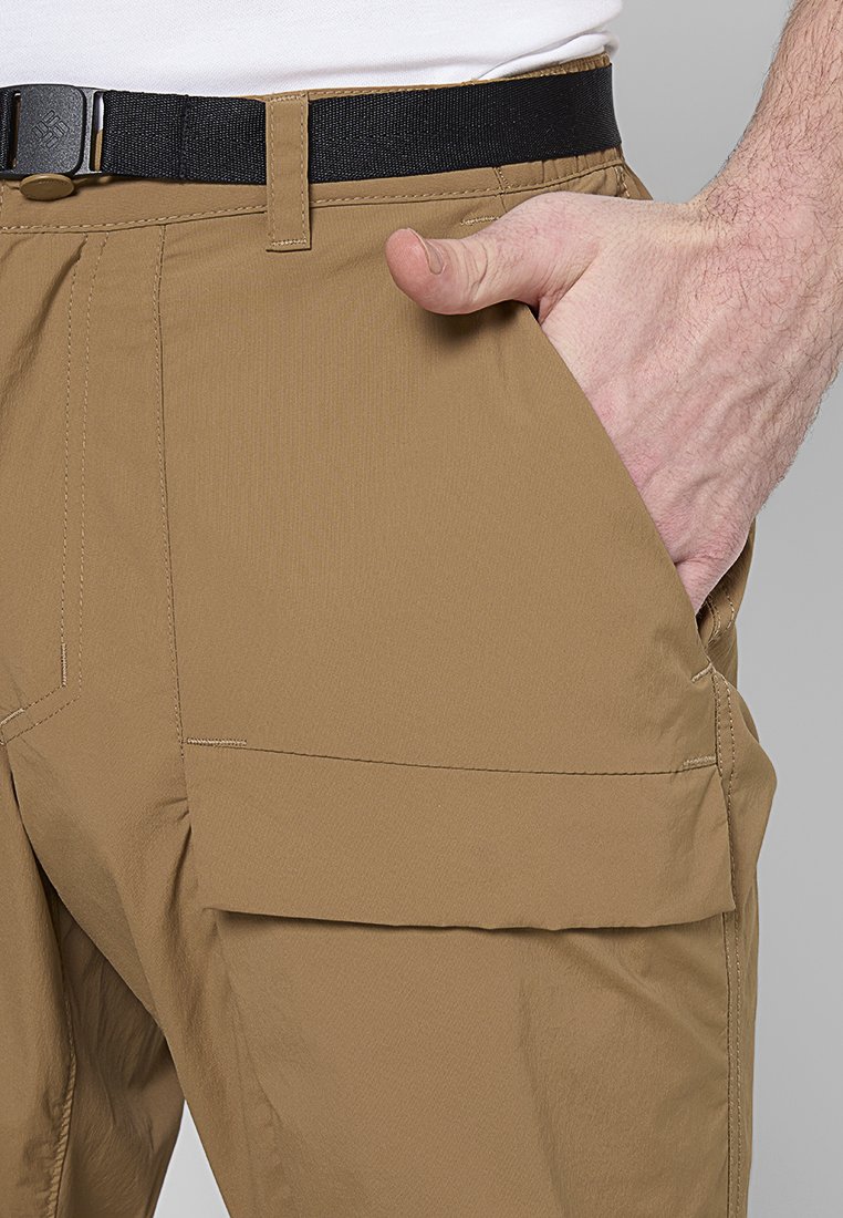 Pantalon cargo beige avec une texture lisse, une poche avant et une ceinture noire. Comprend les passants de ceinture et des détails de couture visibles.