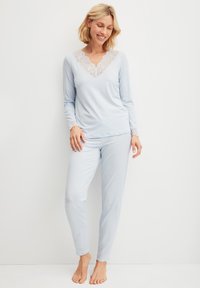Lichtblauw pyjama set met een V-halslijn met kantafwerking en lange mouwen, aansluitende broek ontworpen voor comfort en bewegingsgemak.