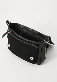 Borsa a spalla in pelle nera con tasca frontale in suede, hardware dorato, chiusura con zip e tracolla regolabile. L'interno ha una finitura testurizzata.