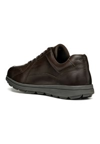 Sneaker in pelle marrone con pannelli laterali texturizzati e colletto imbottito. Presenta una suola in gomma grigia con un motivo battistrada per la presa.
