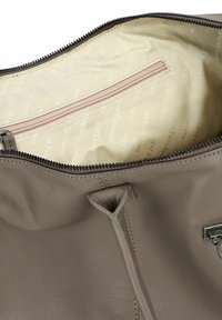 Interno di una borsa in pelle grigia che mostra una fodera beige con una tasca con zip. I dettagli includono una finitura testurizzata e un accento metallico del marchio.