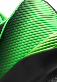 Groene sportschoen bovenkant met gestructureerd, gestreept materiaal en zwarte accenten, en een gladde overlay, die het lichte en ademende ontwerp benadrukt.