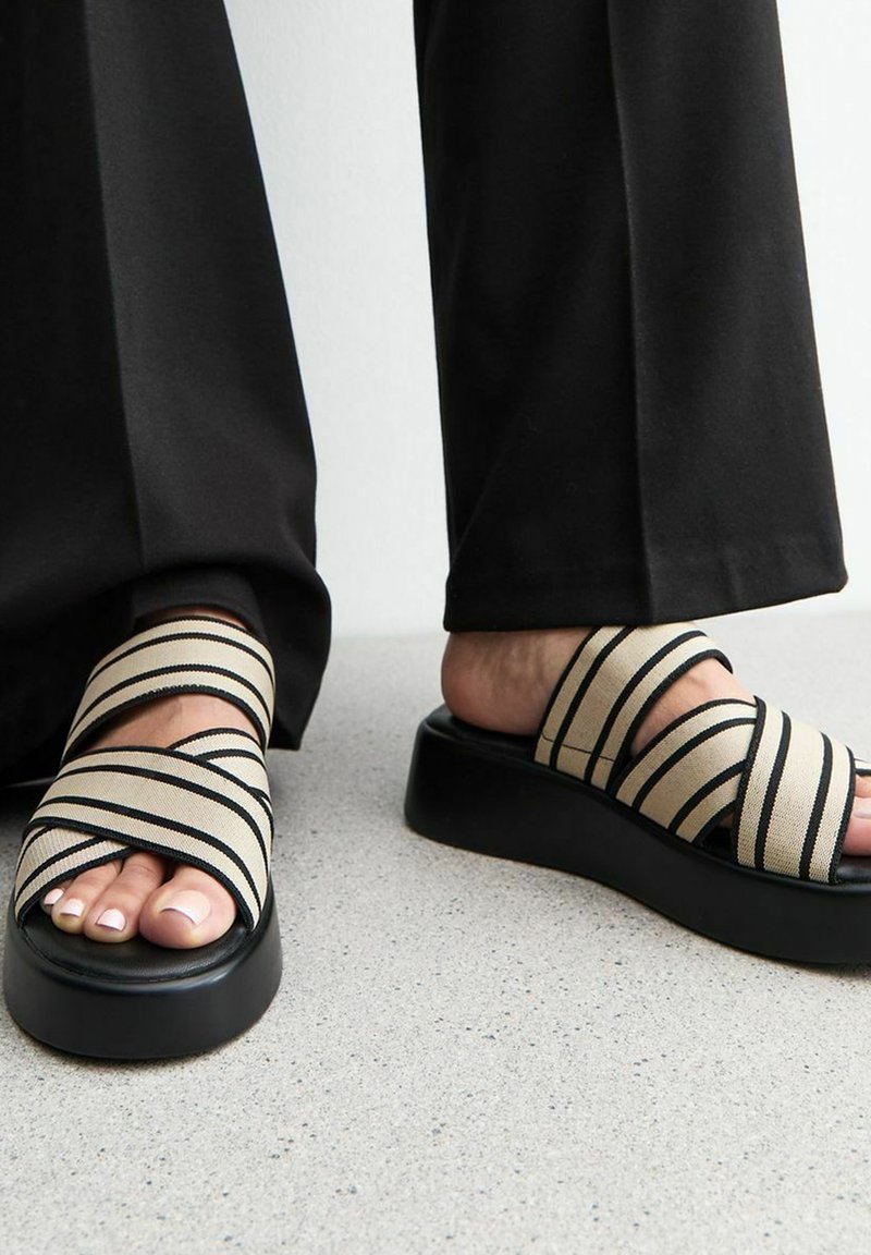 Gestreepte platform slider sandalen met beige en zwarte stoffen bandjes, voorzien van een zwarte chunky zool en een gladde textuur.